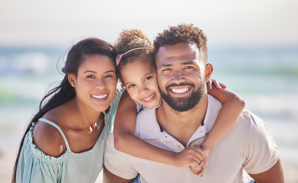 Happy Parents and Child Showcasing Confident Smiles Outdoors – Del Mar Family Dentistry